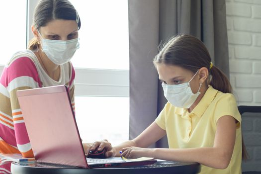 Girl does homework online, mom is watching nearby