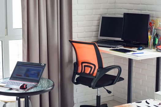 Part of the interior of the room, on the table is a laptop, in the background is a workplace at home