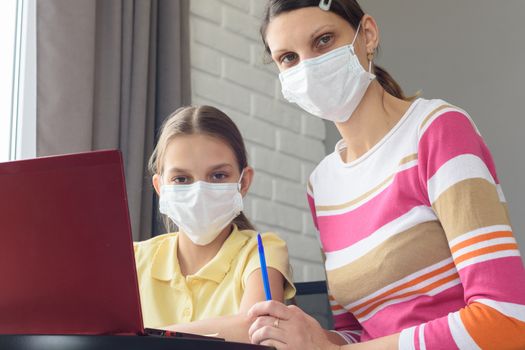 Mom and daughter in medical masks quarantined study online