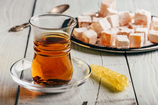 Tea in arabic glass with turkish delight Rahat Lokum over wooden surface