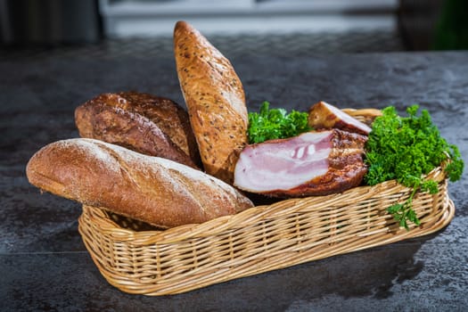 Still life. Bread and smoked meat in a braided basket on the table.