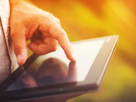 Smart casual man with digital tablet outdoors, close up. Focus on finger. Modern remote work concept.