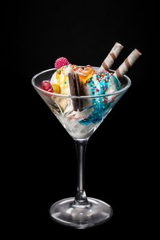 Ice cream balls in a glass with decoration on a black background