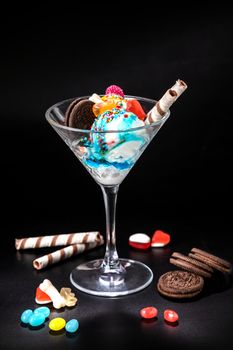 Ice cream balls in a glass with decoration on a black background