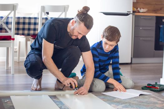 Family relations, fatherhood, parenting, hobby, carpentry, woodwork concept - Father and son making constructing furniture together at home