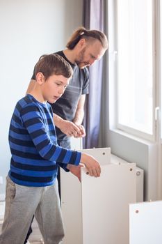 Family relations, fatherhood, parenting, hobby, carpentry, woodwork concept - Father and son making constructing furniture together at home