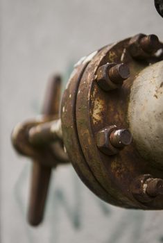 Old weathered gas crane and pipe on the background of a gray wall. Old gas gate of yellow colour is on a pipe and blocks a pipe. The pipeline with cranes for gas giving on the wall