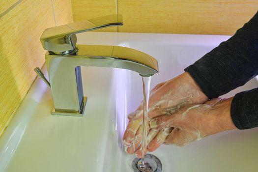 Coronavirus prevention hand hygiene. Corona Virus pandemic protection by cleaning hands frequently. COVID-19. Coronavirus prevention washing hands with soap at bathroom sink man hand hygiene for corona virus pandemic precaution by washing hands frequently for 20 seconds 