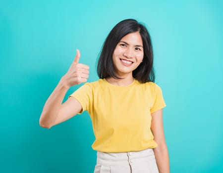 Portrait Asian beautiful young woman standing, She made finger thumbs up, Ok sign to agree and looking at camera, shoot photo in studio on blue background, There was copy space