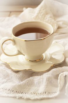 Tea in a white pot of a cup on a white vintage napkin background