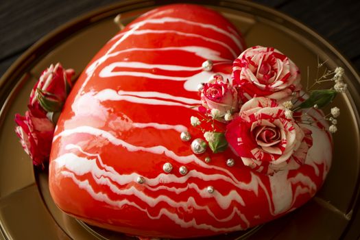 Modern mousse cake in the shape of heart. With roses, closeup