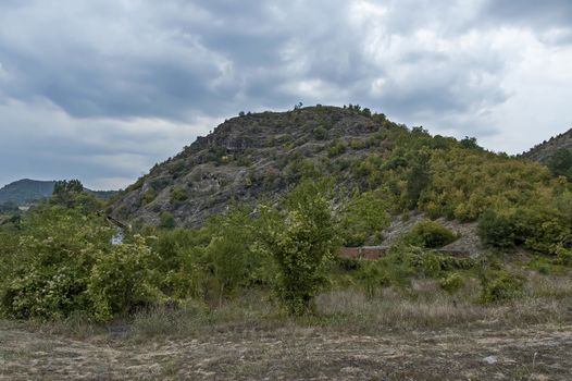 Amazing autumn view of glade, field, peak, deciduous forest, trees and small village in Sredna gora mountain, Bulgaria