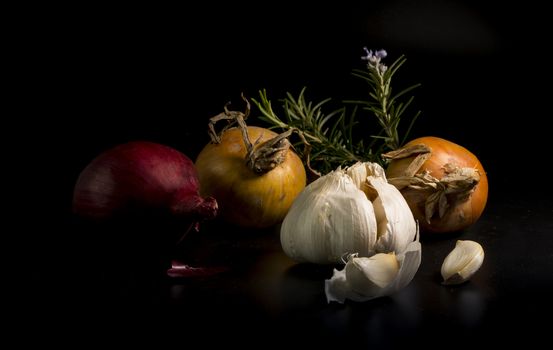 still life of Garlic and onion vegetables with rosemary spice ion black background
