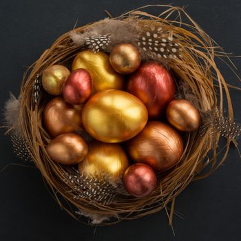 Happy Easter holiday greeting symbol stylish natural wooden grass nest with golden quail eggs on black background