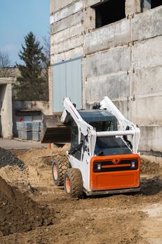 White skid steer loader at a construction site working with a soil. Industrial machinery. Industry