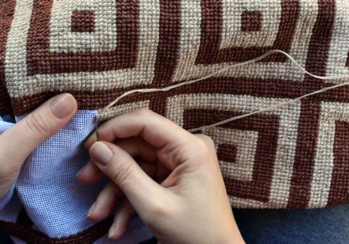 Woman embroidering traditional pattern with geometric design