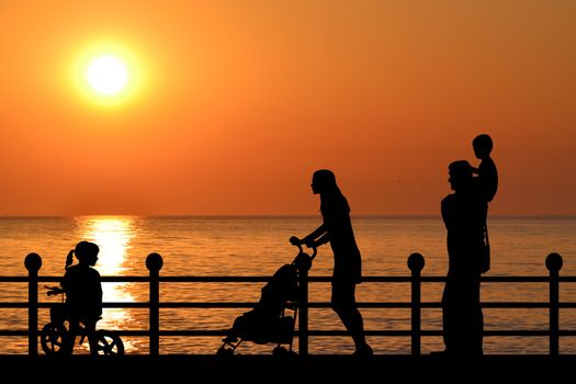 Family silhouette on the waterfront promenade at sunset