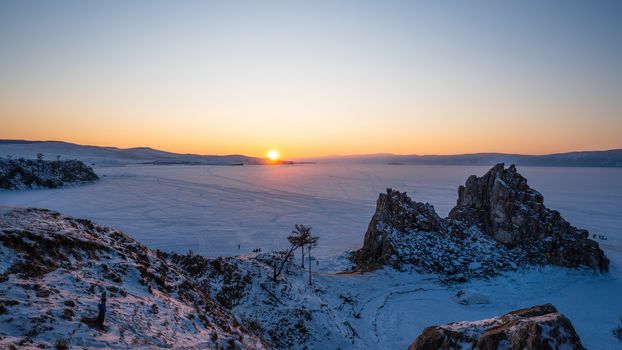 Sunset scene at cape of Burkhan (Shaman Rock) with frozen ice Lake Landscape. Lake Baikal, Russia