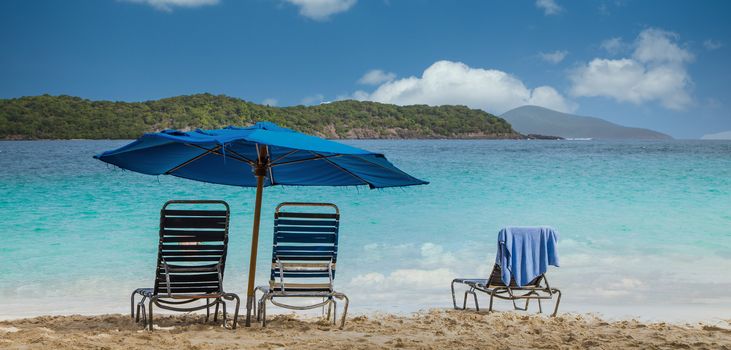 Chairs under blue umbrella on a tropical beach
