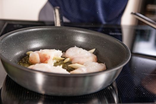 hands of cook preparing food in a frying pan with meat and vegetables