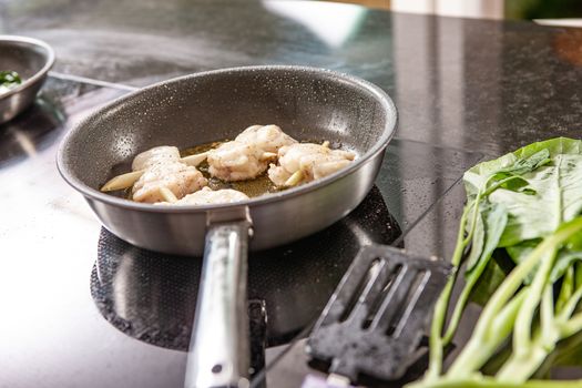 hands of cook preparing food in a frying pan with meat and vegetables