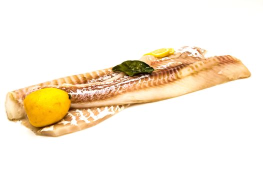 Two cod fillets with a lemon on a white background