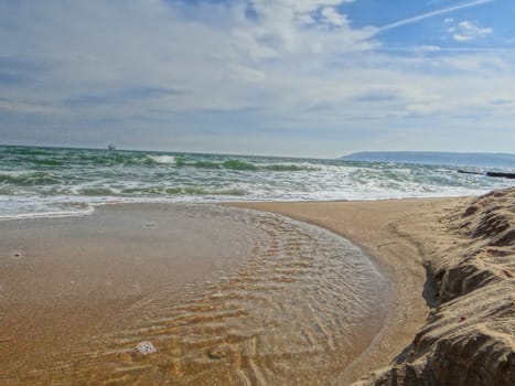 The beautiful golden sand flooded by the crystal sea water with some clouds for background.