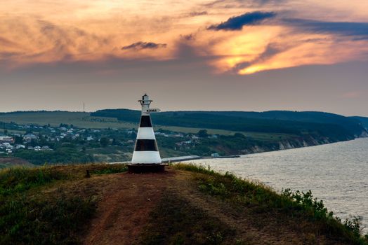 Beacon with the inscription 'Kama' on the hill in sunset light