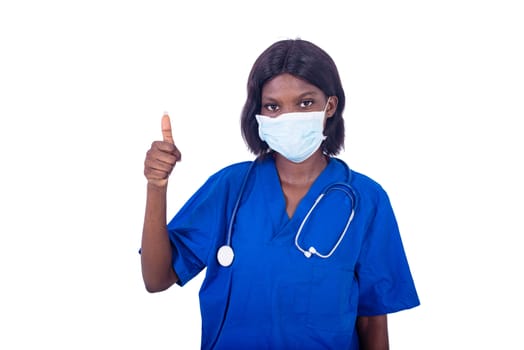 beautiful astonished young woman, doctor in uniform showing her thumb to the camera.