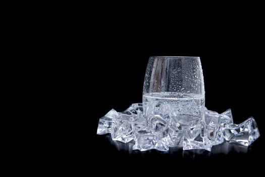 glass of water with ice and bubbles on black background. Shot from side view