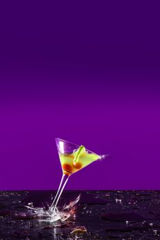 New Years concept of a crashing alcohol glass with purple background and yellow drink