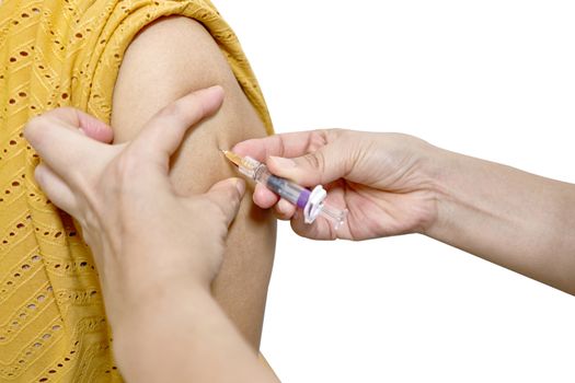 Hand of nurse holding hypodermic syringe injected vaccine of flu with left shoulder of woman in brown blouse isolated on white background. Healthcare and medical concept photography.