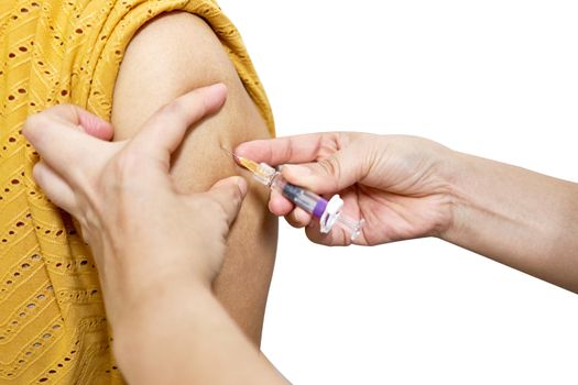 Hand of nurse holding hypodermic syringe is injecting vaccine of flu with left shoulder of woman in brown blouse isolated on white background. Healthcare and medical concept photography.