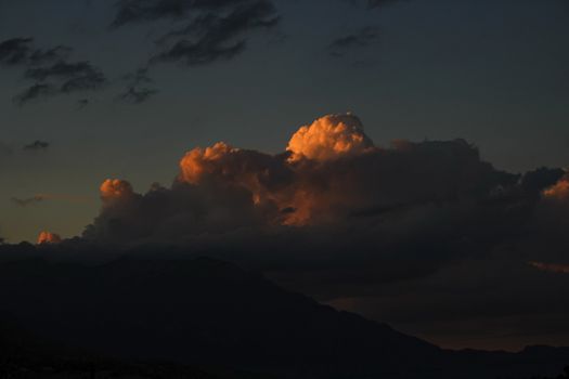 dark sky with orange storm clouds over mountain range, with dramatic clouds