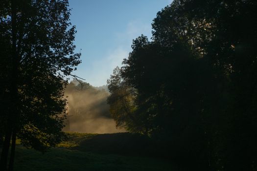 foggy valley in switzerland during sunrise with run rays and shadows