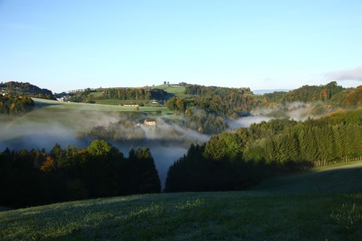 foggy valley in switzerland during sunrise with fog in the valley