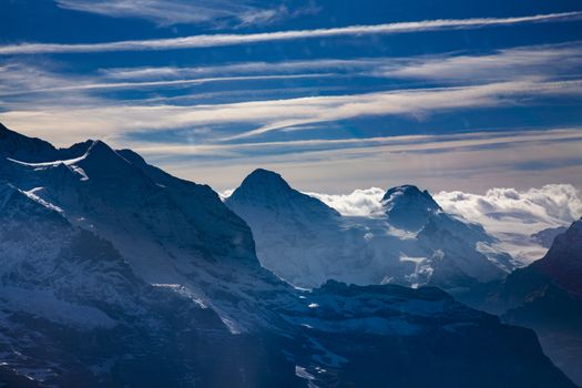 Three famous Swiss mountain peaks, Eiger, Mönch and Jungfrau with blue sky and clouds