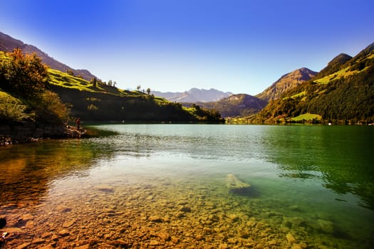 lake lungern Switzerland - famous fishing lake in Switzerland. Stones and reflection in water