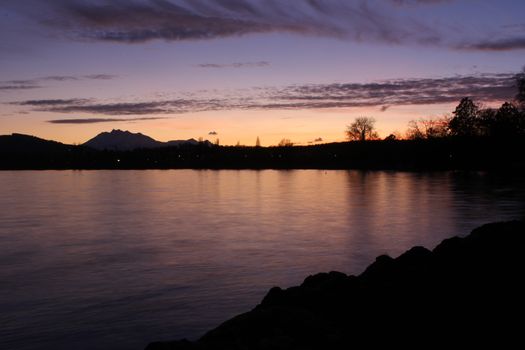 twilight by the lake in Cham, Zug with the swiss alps, with reflection in lake