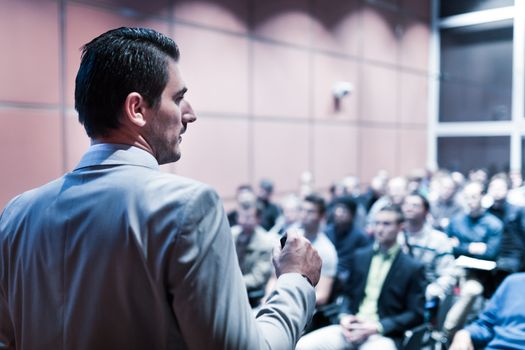 Speaker giving a talk on corporate business conference. Unrecognizable people in audience at conference hall. Business and Entrepreneurship event.