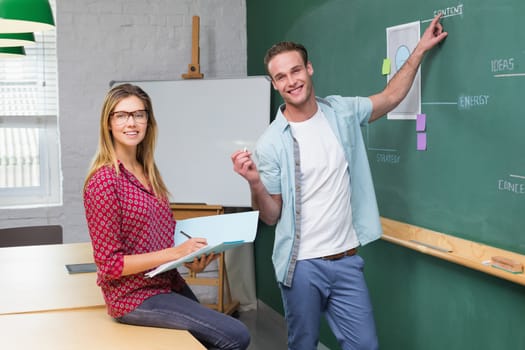 Young creative business people at work against blackboard at office