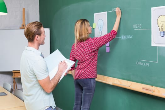 Young creative business people at work against blackboard at office