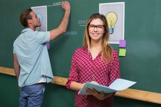 Young creative business people at work against blackboard at office