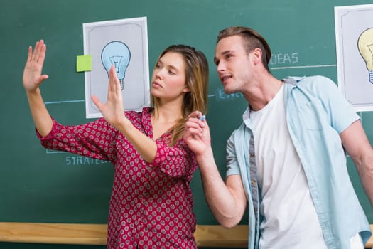 Young creative business people at work against blackboard at office