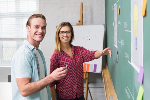 Young creative business people at work by blackboard at office