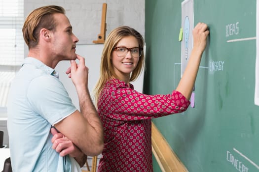 Young creative business people at work by blackboard at office