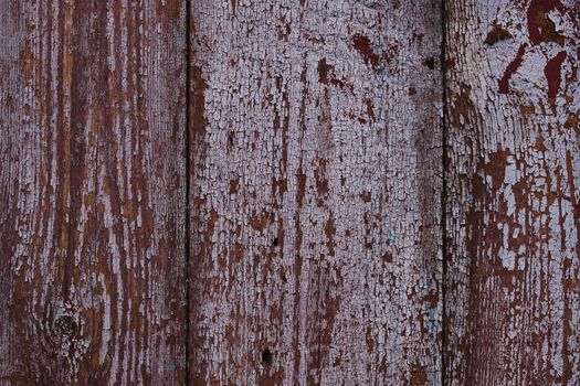 Old red wooden texured door surface closeup. Relief on surface. Stock photo of old wooden door pattern of aged boards with scratches. Red and gray colors on photo.