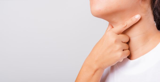 Asian beautiful woman Sore Throat or thyroid gland problem her useing Hand Touching Ill Neck on white background with copy space, Medical and Healthcare concept