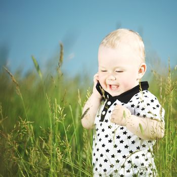 Little cute boy in green grass meadow call by phone