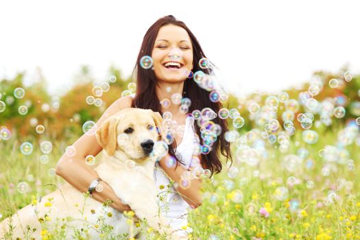 Happy woman and her lablador dog in green grass meadow